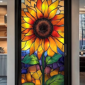 Puede incluir: Una ventana de vitrales con un gran girasol con pétalos amarillos, naranjas y rojos. El girasol está rodeado de piezas más pequeñas de vitrales en varios colores, incluyendo azul, verde y morado.