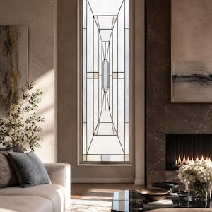 May include: A tall, rectangular window featuring a geometric stained glass design with black lead lines, clear glass panes, and small accents of light beige and pale blue glass, set within a neutral-toned wall in a residential interior space.