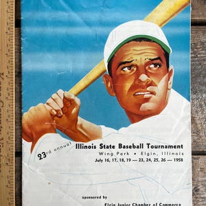 Könnte beinhalten: Ein Vintage-Plakat, das das 23. jährliche Illinois State Baseball Tournament bewirbt. Das Plakat zeigt einen Baseballspieler in einer weißen Uniform mit einem Schläger und den Text: "23. jährliches Illinois State Baseball Tournament, Wing Park, Elgin, Illinois, 16., 17., 18., 19. Juli - 23., 24., 25., 26. - 1958, gesponsert von der Elgin Junior Chamber of Commerce."