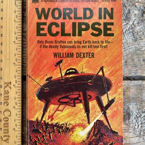 May include: Vintage paperback book titled "World in Eclipse" with a retro science fiction cover. The cover features a red and black illustration of a futuristic vehicle and figures on a fiery landscape. The author's name is William Dexter.