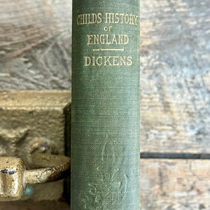 May include: A green book with the title "Childs History of England" and the author "Dickens" on the spine.