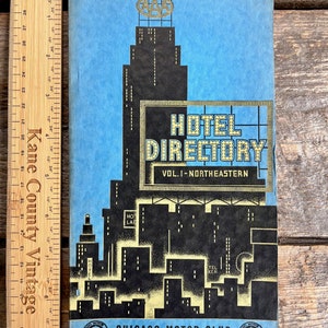 Könnte beinhalten: Ein Vintage-Cover in Blau und Schwarz, das ein Hotelverzeichnis zeigt, das vom Chicago Motor Club herausgegeben wurde. Das Cover zeigt eine stilisierte Stadtlandschaft mit einem hohen Gebäude, das mit dem AAA-Logo gekrönt ist, und einem großen Schild mit der Aufschrift "Hotel Directory Vol. I - Northeastern".