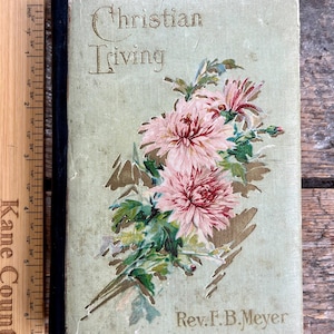 May include: A vintage book titled "Christian Triving" by Rev. F.B. Meyer. The cover features a floral design with pink and white flowers on a green background.