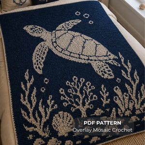 May include: A dark navy blue and cream crochet blanket featuring a sea turtle swimming above coral reefs and seashells. The text on the image reads PDF PATTERN Overlay Mosaic Crochet. The design uses a two-tone color scheme with intricate patterns.
