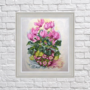 May include: Framed floral embroidery featuring a vibrant arrangement of pink cyclamen flowers in a decorative pot. The artwork showcases detailed stitching with green foliage and a soft, light background. The framed piece is displayed against a white brick wall.
