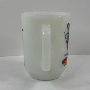 May include: White ceramic mug featuring a colorful Mickey Mouse graphic. The mug has a curved handle and the year "1940" is printed on the side. The mug is a vintage collectible.