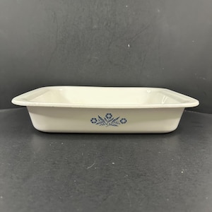 May include: Off-white rectangular baking dish with rounded corners. The dish features a blue floral design on the front. The dish is made of a durable material and is suitable for baking and serving.