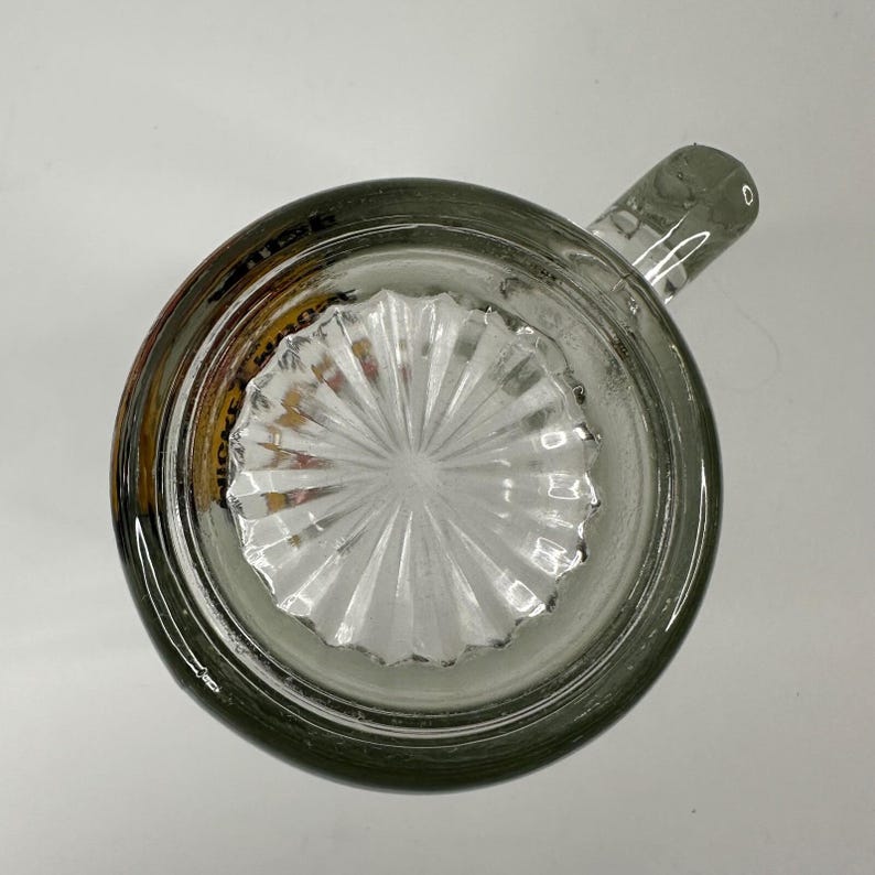 Peut inclure: Une chope &agrave; bi&egrave;re en verre transparent vue directement du dessus, dot&eacute;e d'une anse &eacute;paisse et robuste et d'un motif en &eacute;toile en relief au centre de la base. Le bord circulaire est lisse et le verre pr&eacute;sente une l&eacute;g&egrave;re teinte grise.