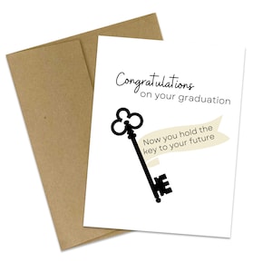 Op de afbeelding: Een afstudeerwenskaart met een kraft papieren envelop. De witte kaart heeft de tekst "Gefeliciteerd met je afstuderen" en een zwarte sleutelafbeelding. De banner luidt "Nu heb je de sleutel tot je toekomst."