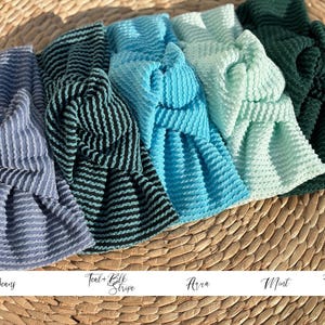 Pu&ograve; includere: Una collezione di fasce per capelli annodate in vari colori, tra cui blu, verde acqua, turchese, menta e verde cacciatore. Ogni fascia presenta un tessuto strutturato e a coste. I colori sono denominati: "Blue Jeans", "Teal + Blk Stripe", "Arra", "Mint" e "Hunter Green".