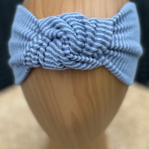 Pu&ograve; includere: Fascia per capelli a righe blu e bianche con un design annodato. La fascia &egrave; realizzata in un tessuto a coste morbido ed &egrave; progettata per essere indossata intorno alla testa. Il colore &egrave; blu chiaro con strisce bianche.