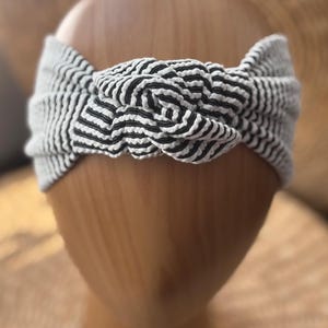 K&ouml;nnte beinhalten: Ein gestreiftes Turban-Haarband in Schwarz und Wei&szlig; mit einem Knotendesign.