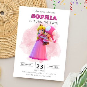 Puede incluir: Una invitaci&oacute;n de cumplea&ntilde;os rosa y blanca con una imagen de dibujos animados de la princesa Peach y Toad de la serie de videojuegos Super Mario Bros. La invitaci&oacute;n dice "&iexcl;&Uacute;nete a nosotros para celebrar que Sophia cumple dos a&ntilde;os!" e incluye la fecha, la hora y el lugar de la fiesta.