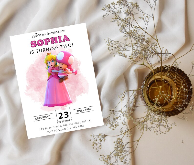 Puede incluir: Una invitaci&oacute;n de cumplea&ntilde;os rosa y blanca con una imagen de dibujos animados de la princesa Peach y un personaje de Toad. La invitaci&oacute;n dice "&iexcl;&Uacute;nete a nosotros para celebrar que Sophia cumple dos a&ntilde;os!" e incluye la fecha, la hora y la informaci&oacute;n de RSVP.