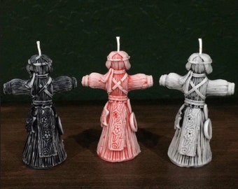 May include: Three handmade candles shaped like traditional folk dolls. The dolls are dressed in black, red, and white clothing with intricate details. The candles are a unique and decorative way to add a touch of folk art to your home.