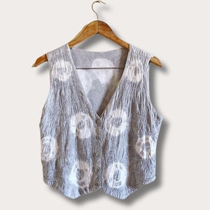 May include: A grey sleeveless vest with a white tie-dye pattern and button closure.
