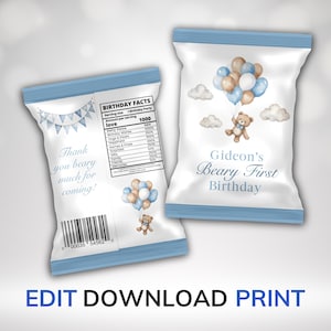 May include: Two white party favor bags with blue trim. One bag features text and a banner, the other has a teddy bear with balloons. The bags are for Gideon's first birthday. The text says "Thank you beary much for coming!"