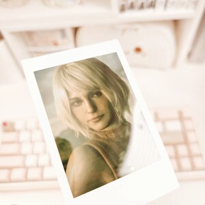May include: A Polaroid photo of a woman with short, blonde hair. She is wearing a brown sweater and looking directly at the camera.
