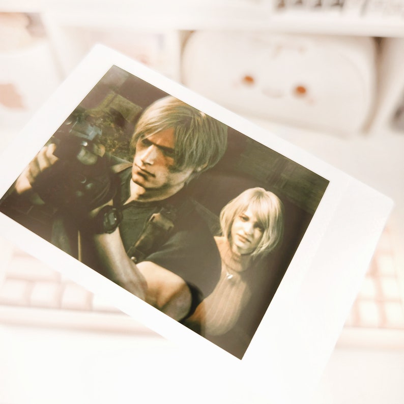 May include: A black and white photo of a man and a woman. The man is holding a gun and looking at the camera. The woman is looking at the man. The photo is in a Polaroid frame.