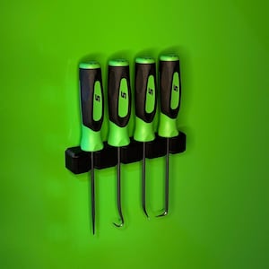 May include: Four black and green pick tools are displayed on a black holder against a bright green background. The tools have black handles with green accents and the letter "S" printed on them. The tips of the tools are different shapes.