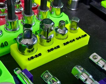 May include: A bright neon green plastic organizer tray holding various chrome-plated steel socket adapters and extensions. The tray features black printed text labels for each tool, including 1/2-3/8, 3/8-1/2, and 3/8-1/4 size designations.