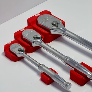 May include: Three red plastic tool holders with three ratcheting wrenches. The wrenches are labeled 1/4, 3/8, and 1/2. The wrenches are silver and have black handles.