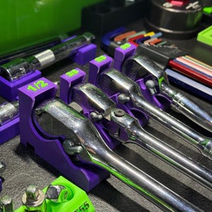 May include: Purple and green tool holders with a set of wrenches. The wrenches are labeled 1/2, 3/8, and 1/4.