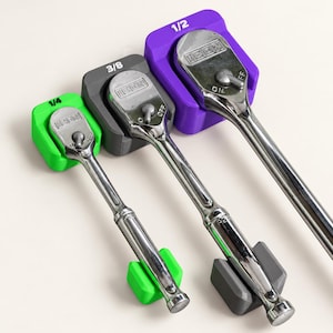 May include: Three chrome ICON ratchets in 1/4, 3/8, and 1/2 inch drive sizes. Each tool is secured in a color-coded plastic holder: bright green for 1/4, dark gray for 3/8, and purple for 1/2. The metal heads feature ON and OFF switches.
