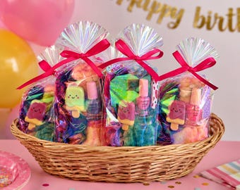 Puede incluir: Una cesta de mimbre llena de bolsas de regalo envueltas en celofán atadas con cintas rojas. Cada bolsa contiene artículos coloridos, incluyendo esmalte de uñas y jabones con forma de paleta. El fondo incluye globos y una pancarta que dice "happy birth".