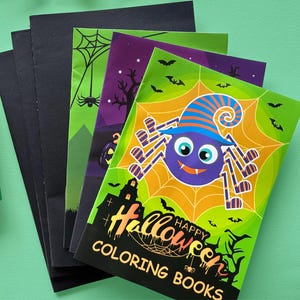Puede incluir: Una pila de libros para colorear de Halloween con una ara&ntilde;a morada que lleva un sombrero de bruja a rayas azules y naranjas sobre una telara&ntilde;a amarilla. La portada muestra una silueta de casa encantada negra, murci&eacute;lagos y el texto HAPPY HALLOWEEN COLORING BOOKS.