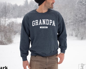 Puede incluir: Una sudadera gris oscuro jaspeada con el texto "GRANDPA EST. 2023" en blanco.