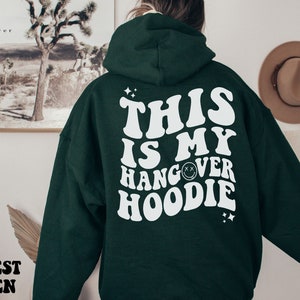May include: Forest green hoodie with white text that reads "This is my hangover hoodie" with a smiley face graphic.