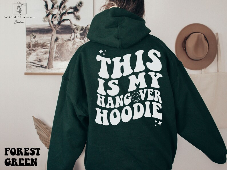 May include: Forest green hoodie with white text that reads "This is my hangover hoodie" with a smiley face graphic.