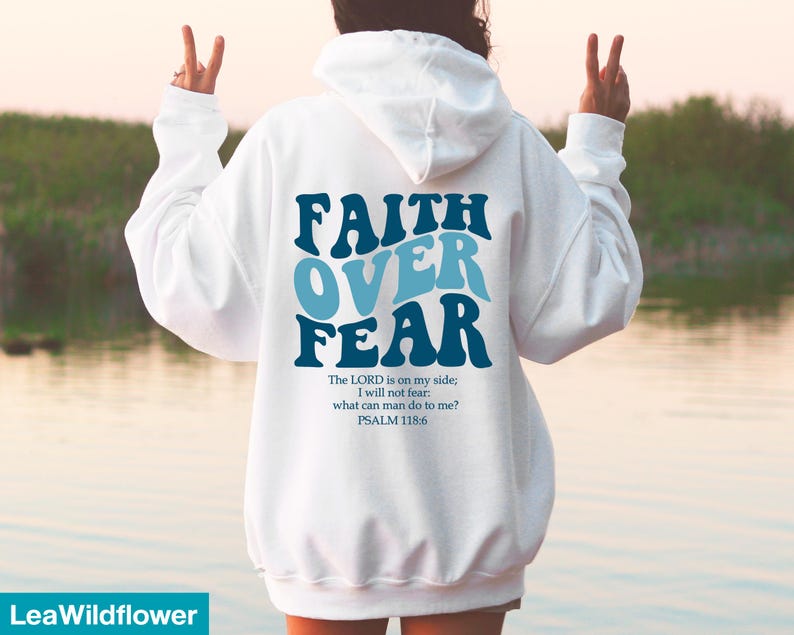 K&ouml;nnte beinhalten: Wei&szlig;er Kapuzenpullover mit dem Text "FAITH OVER FEAR" in Blau und Hellblau. Darunter steht das Zitat "The LORD is on my side; I will not fear: what can man do to me? PSALM 118:6".