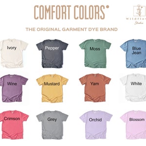 Puede incluir: Una colecci&oacute;n de 12 camisetas de varios colores, incluyendo marfil, pimienta, musgo, azul vaquero, vino, mostaza, &ntilde;ame, blanco, carmes&iacute;, gris, orqu&iacute;dea y flor. Las camisetas est&aacute;n dispuestas en una cuadr&iacute;cula y cada una tiene un color diferente. El texto "COMFORT COLORS" y "THE ORIGINAL GARMENT DYE BRAND" se muestra en la parte superior de la imagen. El texto "Wildflower Studio" se muestra en la esquina superior derecha de la imagen.