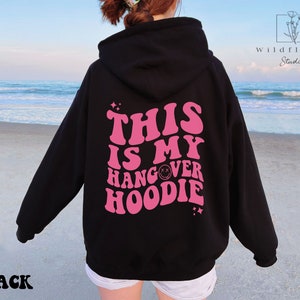 May include: Black hoodie with a pink graphic that says "This is my hangover hoodie" with a smiley face in the word hangover.