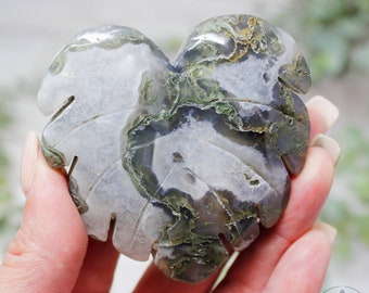 May include: A heart-shaped green and white agate carving in the shape of a leaf. The agate has a natural, organic pattern.