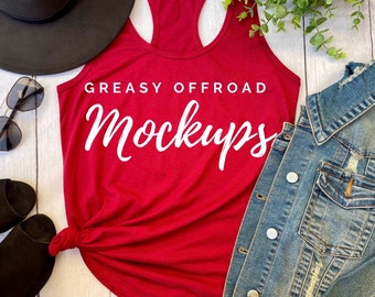 May include: A red tank top with the text "GREASY OFFROAD Mockups" in white script. The tank top is styled with a black hat, sunglasses, black sandals, and a denim jacket.
