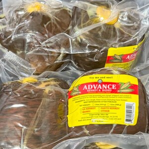 Peut inclure: Trois paquets sous vide de pâte de maïs fermentée brun foncé, connus sous le nom de Kenkey et Banku. Chaque paquet porte une étiquette jaune avec le texte ADVANCE KENKEY & BANKU, indiquant les ingrédients, le poids net de 454g ou 908g et les contacts.