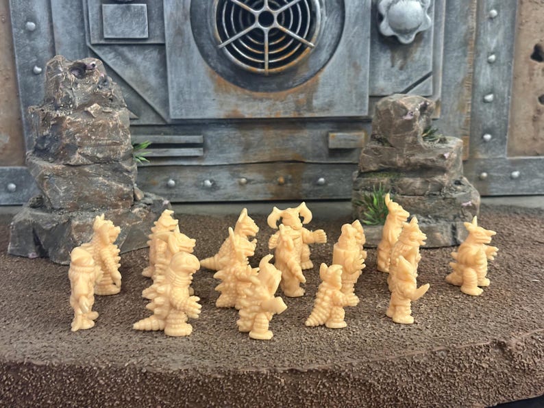 Peut inclure: Une collection de petites figurines de monstres en plastique beige clair non peintes, dispos&eacute;es en groupe. Chaque figurine pr&eacute;sente des &eacute;cailles reptiliennes, des pointes et des cornes distinctes, avec des postures bip&egrave;des et des traits uniques.