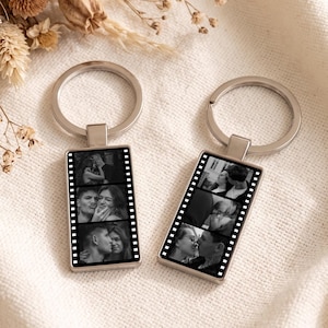 May include: Two rectangular metal keychains featuring a film strip design. Each keychain displays three black and white photographs of a couple in a vertical sequence. The keychains have a silver-toned metal ring attached to the top for keys.