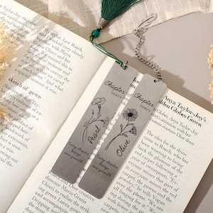 Könnte beinhalten: Zwei rechteckige Lesezeichen aus silberfarbenem Metall auf einem offenen Buch. Eines hat eine grüne Quaste, eine Blumenillustration, den Namen Pearl und den Text Chapter Thirty und Every chapter brings new growth. Das andere hat einen Federanhänger, eine Gänseblümchenillustration, den Namen Olive und den Text Chapter Thirty und Every chapter brings new growth.