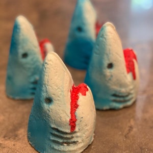 Large shark bath bomb comes with a shark charm inside the bath bomb. The bath bomb will also turn your bath water bloody red, simulating a shark attack!