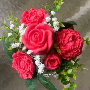 May include: A bouquet of red roses and peonies with white baby's breath and green foliage.