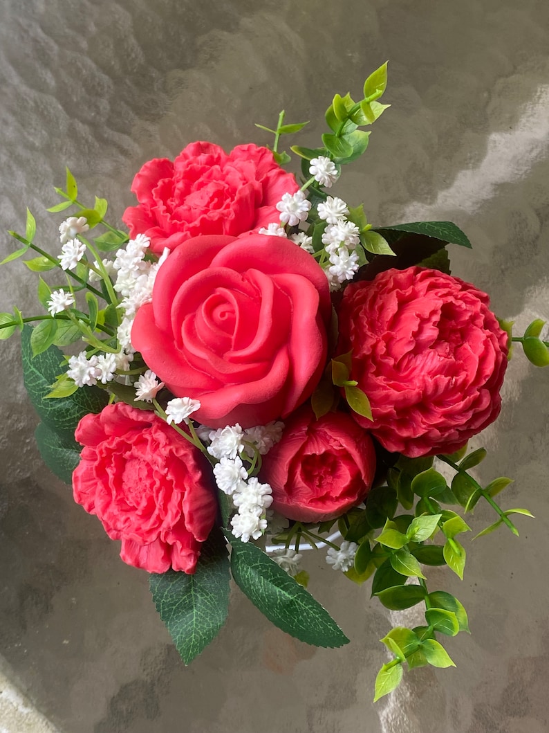 May include: A bouquet of red roses and peonies with white baby's breath and green foliage.