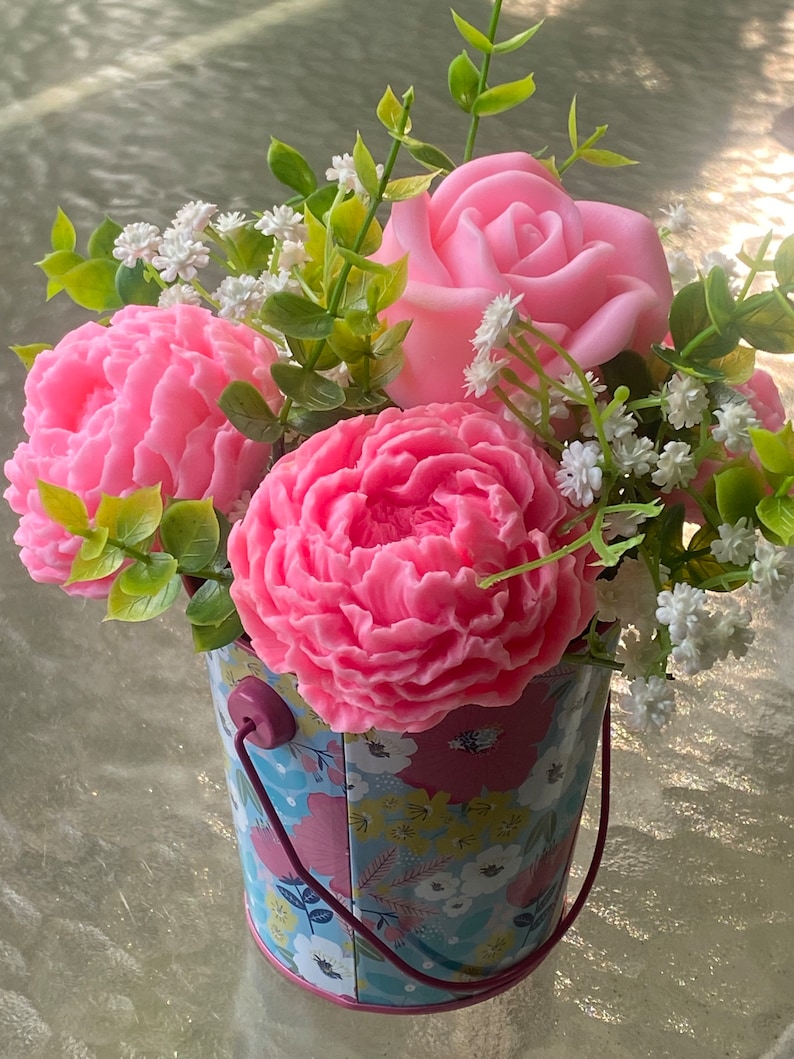 May include: A pink rose and two pink peonies in a floral patterned metal bucket with a pink handle.