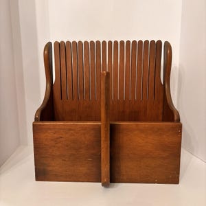 Peut inclure: Un guide-tranche à pain en bois brun moyen doté d'une base rectangulaire solide, d'un séparateur central vertical et d'un panneau arrière haut avec de nombreuses fentes verticales régulièrement espacées pour guider un couteau.