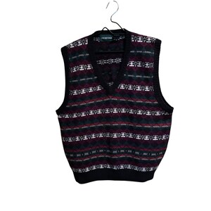 May include: A vintage sweater vest with a V-neck design. The vest features a pattern of burgundy, green, white, and black geometric shapes. The vest is hanging on a black hanger. The brand name "CRICKETEEN" is visible on the label.