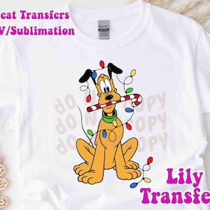 May include: White t-shirt featuring a cartoon Pluto dog holding a candy cane, adorned with Christmas lights. The design includes the text "do copy" in the background and "Heat Transfers HTV/Sublimation" and "Lily Transfers" in pink.