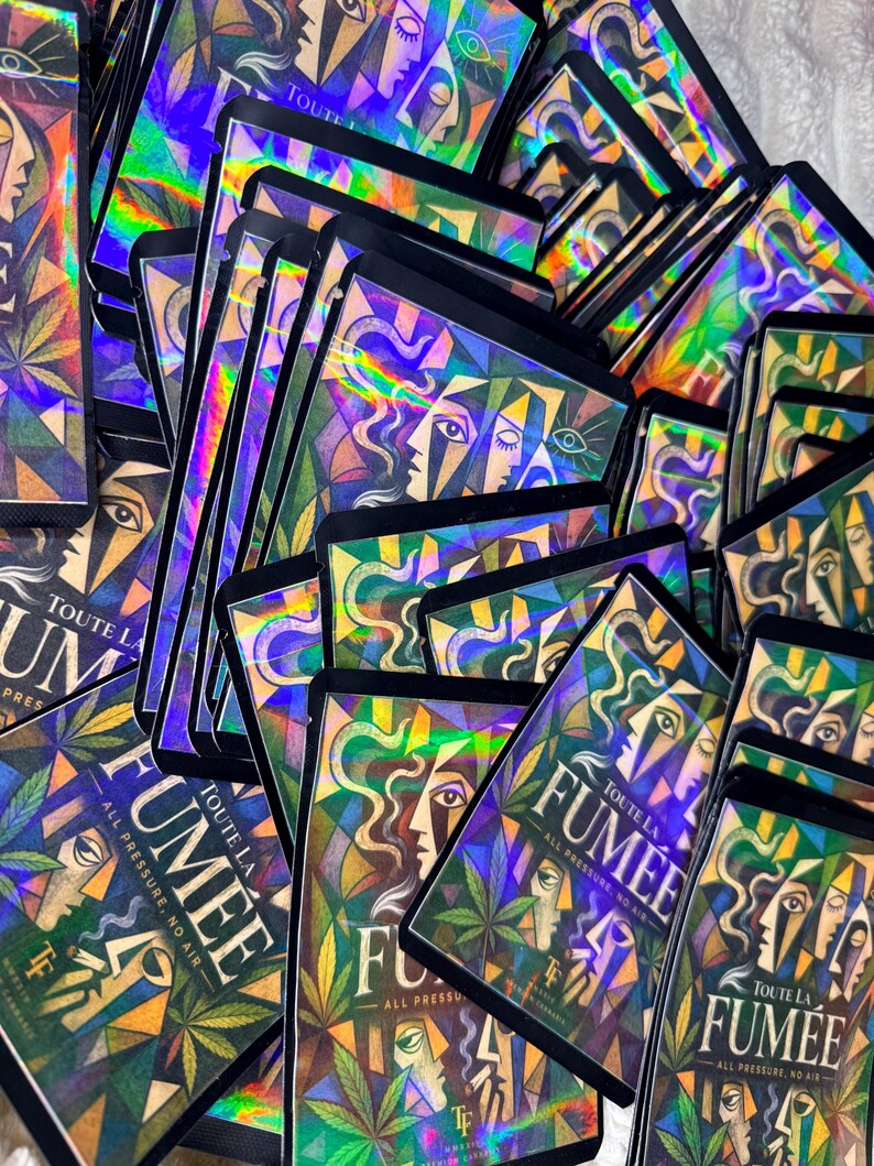 May include: A collection of rectangular holographic product pouches featuring a geometric illustration of faces and cannabis leaves. The text on each pouch reads TOUTE LA FUMEE, ALL PRESSURE, NO AIR, and includes the initials TF at the bottom.